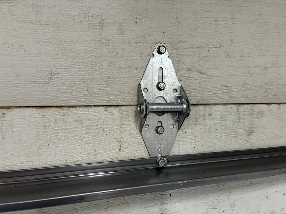 Close-up of a sectional garage door hinge above a horizontal reinforcement strut
