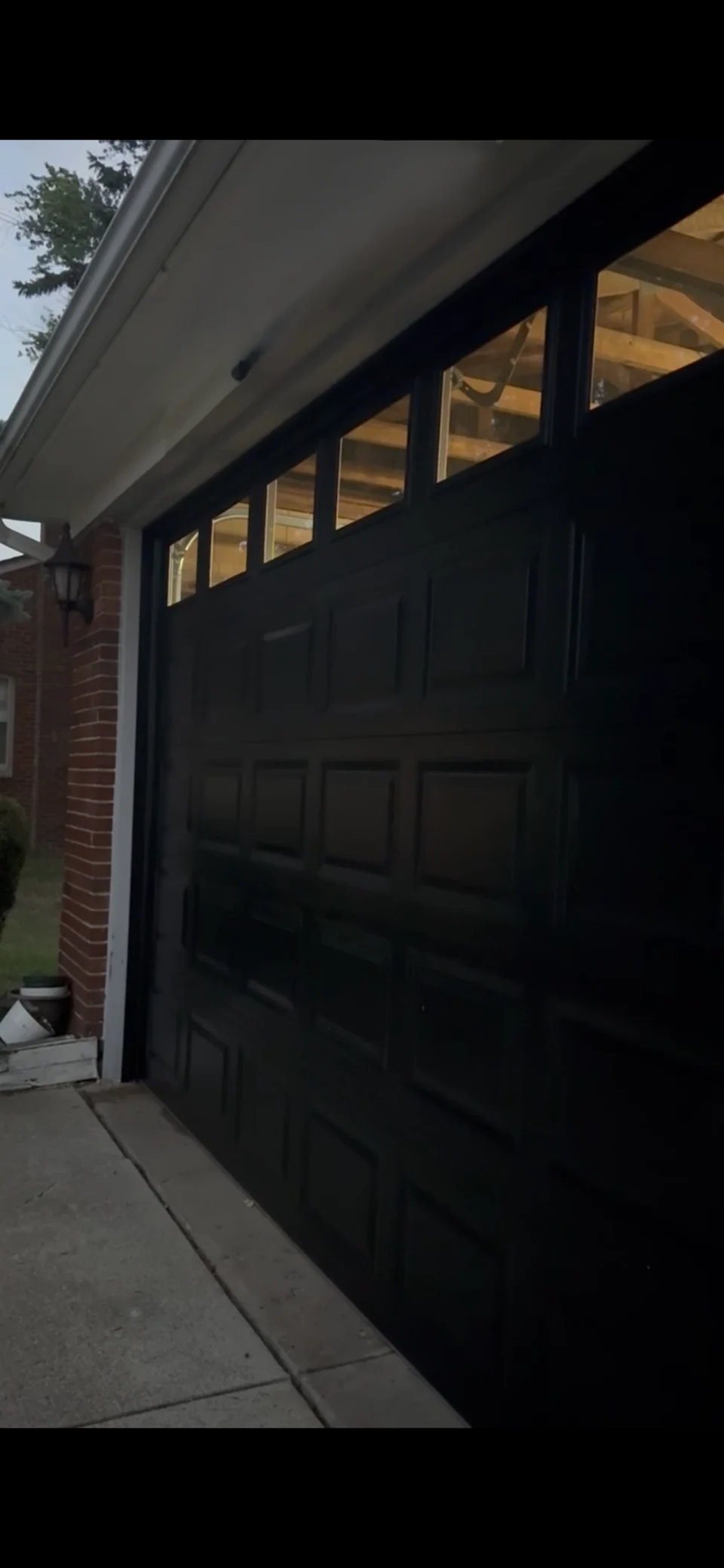 New black carriage-style garage door with upper window panels