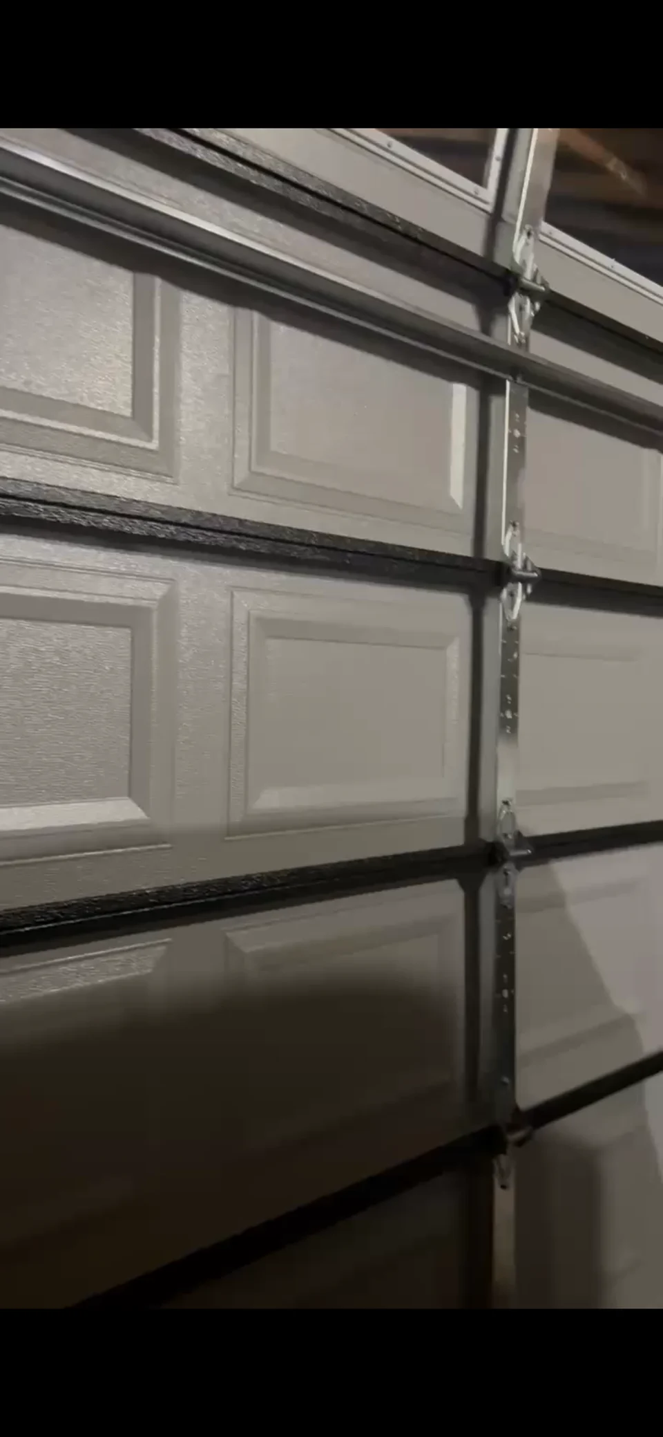 Close-up of garage door section hinges and vertical track
