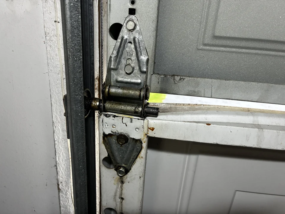 Old garage door hinge showing wear and rust before replacement