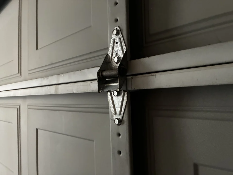 Old garage door hinge showing wear before replacement