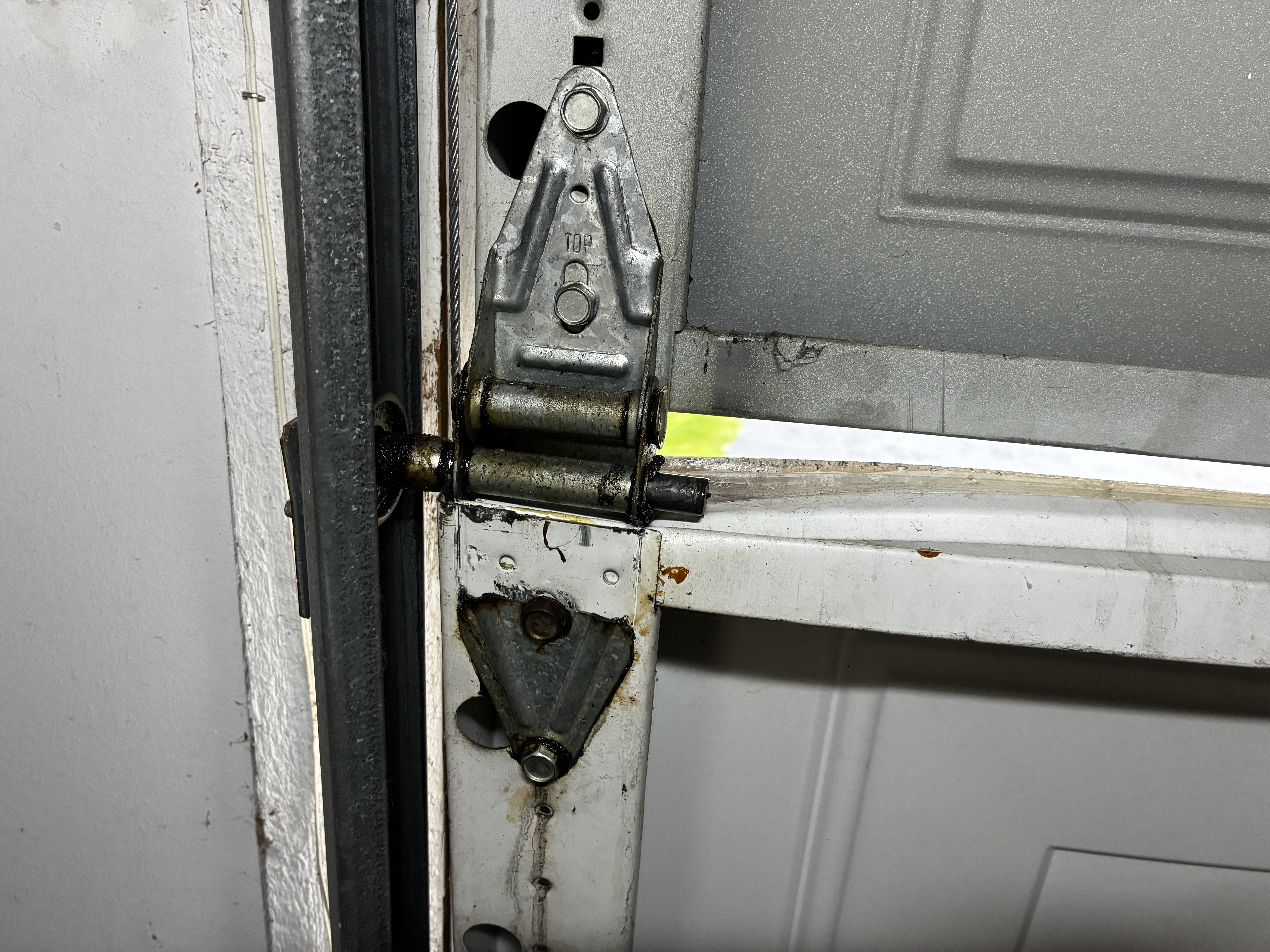 Old garage door hinge showing wear and rust before replacement