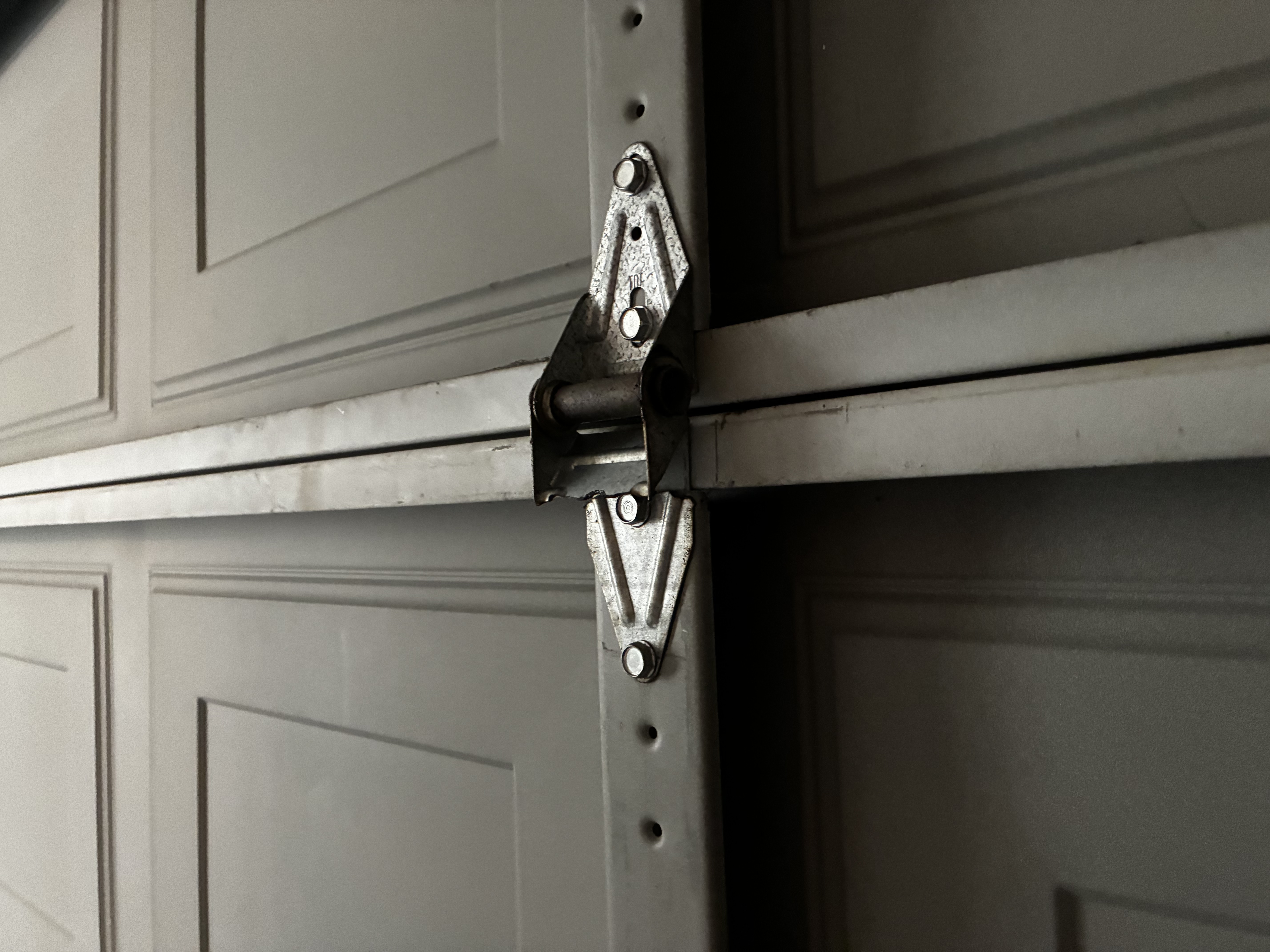 Old garage door hinge showing wear before replacement